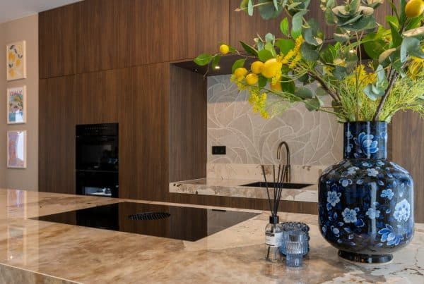 Sfeerbeeld van een luxe keuken, voorzien van kookeiland met dekton khalo werkblad en walnoot kastenwand