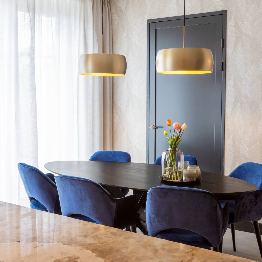 ovale zwart eiken eettafel, gecomplementeerd met design plafonlampen en blauwe eettafelstoelen