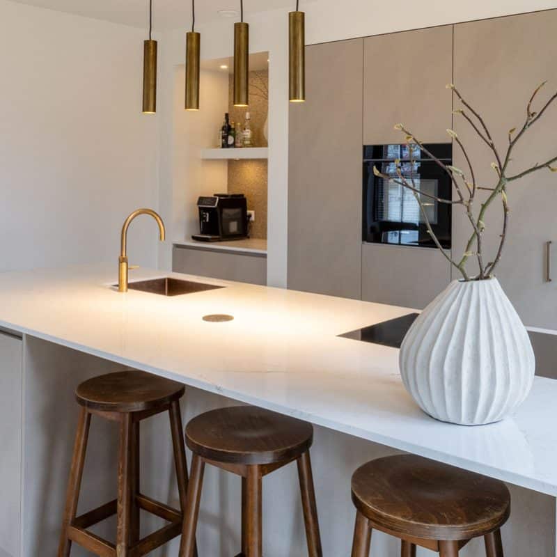 Impressie van een luxe grijs wit keuken met gouden accenten. De keuken heeft een koffiecorner met luxe koffiemachine.